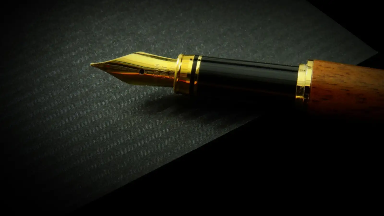 Füllfeder mit goldener Spitze auf dunklem Papier