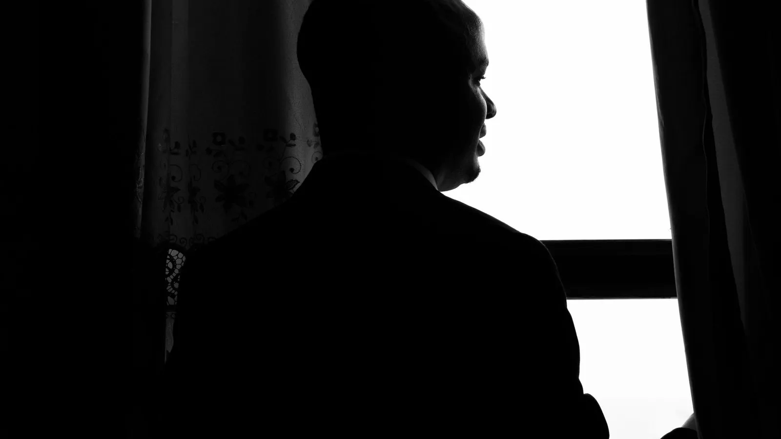 Silhouette eines Mannes neben einem Fenster in Schwarzweiß
