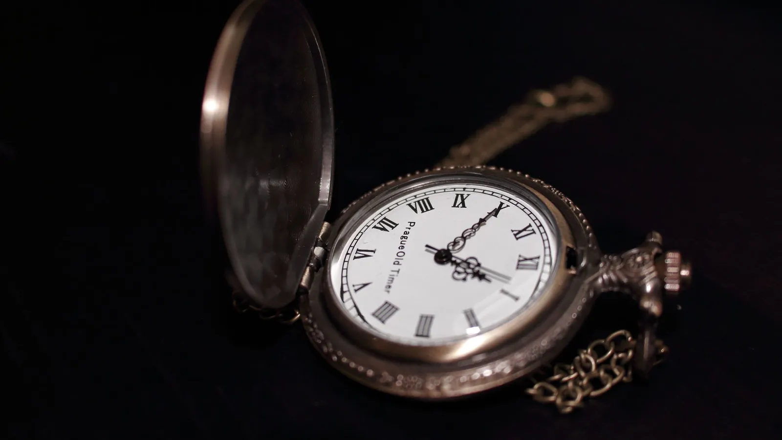 Offene Taschenuhr mit Kette auf dunklem Grund