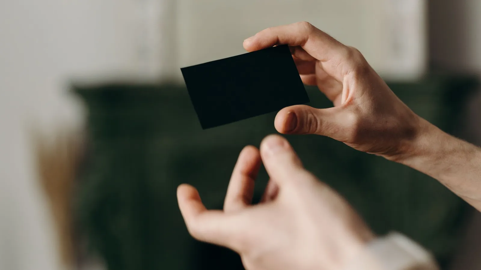 Eine schwarze Karte wird von einer Hand in eine andere gegeben