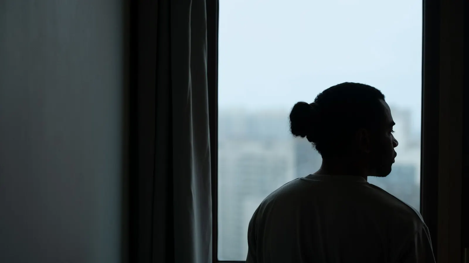 Silhouette eines Mannes am Fenster mit Blick auf die Straße